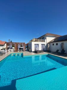 a swimming pool with blue water in front of a house at CasaBlanca vendégház in Abádszalók