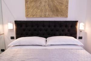 uma cama com uma cabeceira preta e duas almofadas brancas em T-House Roma em Roma
