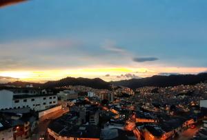 a view of a city at night with the sun setting at Hostal Triangulo del Café in Manizales