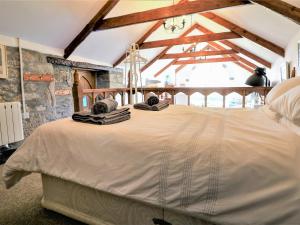 a bedroom with a large white bed with wooden beams at Trevenning Chapel in Michaelstow