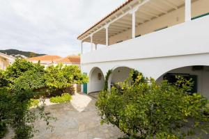 a courtyard of a white building with trees and bushes at Aria Apartments in Spetses