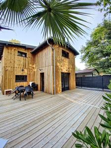 une grande terrasse en bois avec un bâtiment en arrière-plan dans l'établissement Villa Chantaco Bassin Arcachon, à Gujan-Mestras