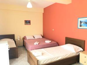 two beds in a room with orange walls at Veizi's Apartments in Himare
