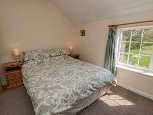 Schlafzimmer mit einem Bett und einem Fenster in der Unterkunft Bellafax Cottage in Kirby Misperton