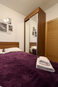 sypialnia z fioletowym łóżkiem z lustrem w obiekcie Apartman Zlatibor Renome w mieście Zlatibor