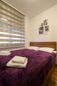 sypialnia z fioletowym łóżkiem i ręcznikami w obiekcie Apartman Zlatibor Renome w mieście Zlatibor