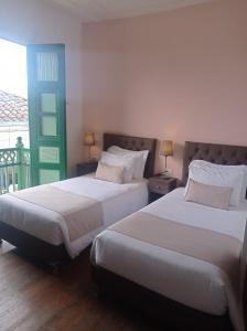 two beds in a hotel room with a green door at Hotel Gio in Sonsón