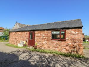 a small brick house with a red door at 1 Pines Farm Cottages in Ulleskelf