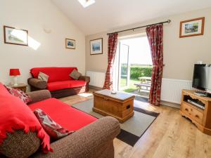 a living room with a red couch and a tv at 2 Pines Farm Cottages in Ulleskelf