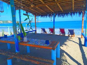 a table and chairs on a beach with the ocean at Hospedaje Algarrobo Machalilla in Machalilla