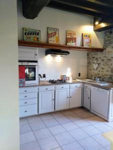 una cocina con armarios blancos y electrodomésticos blancos en Les Ecuries, traditional stone farmhouse with pool en Marquixanes
