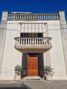 ein weißes Gebäude mit einer Holztür und einem Balkon in der Unterkunft Casa Ippazia in Tiggiano