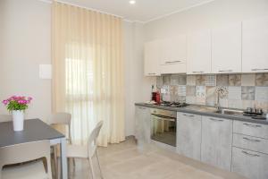 een keuken met witte kasten, een wastafel en een tafel bij Aqua Sea Relais, Luxury Apartment & Pool in Vieste