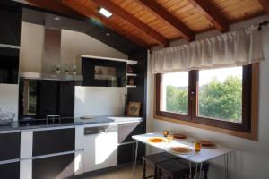 ゴンドマールにあるPedra Moura Casa Ruralのキッチン(白黒のキャビネット、テーブル付)
