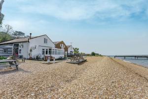 een gebouw en picknicktafels op een rotsachtig strand bij West Sea View No 5 in Yarmouth