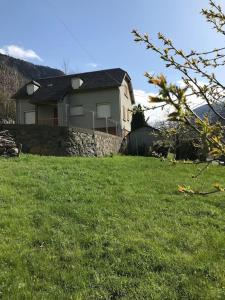 una casa en una colina con un campo de césped verde en Maison de montagne proche Gavarnie 12-14 personnes, en Gèdre