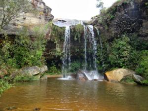 a waterfall in the middle of a pool of water at Cachoeira do Alemão - Recanto dos Arcos in Balsa Nova