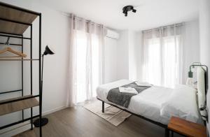 um quarto branco com uma cama e janelas em Apartamentos la Encarnación em Ronda