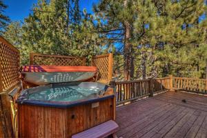 a hot tub on a wooden deck with trees at 015 - Hidden Bridge Cabin in Big Bear Lake