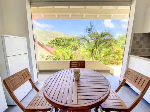 un tavolo in legno con sedie in una stanza con una grande finestra di Beautiful suite S11, pool, sea view, Pinel Island a Cul de Sac