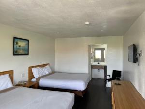 a hotel room with two beds and a desk at Palms Inn & Suites in Palmdale +17 photos