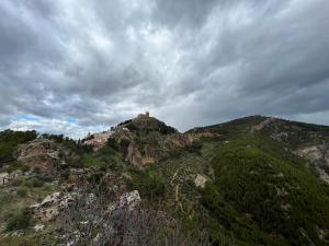 um castelo no topo de uma montanha sob um céu nublado em Alquería de Segur a em Segura de la Sierra