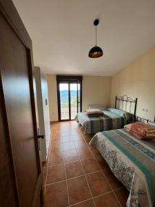 1 dormitorio con 2 camas y puerta a un balcón en Alquería de Segur a, en Segura de la Sierra