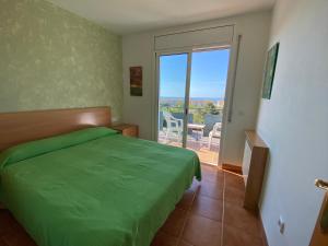 a bedroom with a green bed and a balcony at house on the beach in Calafell