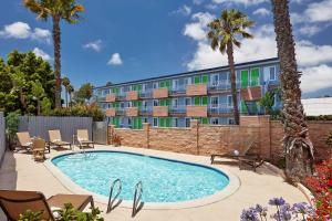 einem Pool vor einem Gebäude mit Palmen in der Unterkunft SureStay Hotel by Best Western San Diego Pacific Beach in San Diego