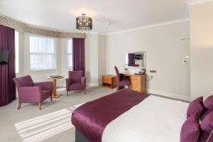 a hotel room with a bed and chairs and a desk at New Continental Hotel; Sure Hotel Collection by Best Western in Plymouth