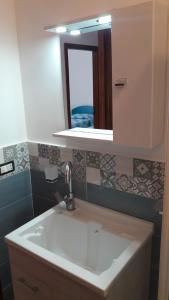 een badkamer met een witte wastafel en een spiegel bij Pecciolo Port Apartaments in Milazzo