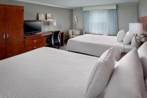 a hotel room with two beds and a flat screen tv at Sonesta Select Tinton Falls Eatontown in Tinton Falls