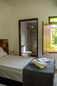 a bedroom with a bed and a bathroom with a sink at Marezal Suítes in Pôrto de Pedras