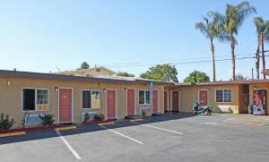 un edificio con puertas rojas en un aparcamiento en Royla Motel en Pomona