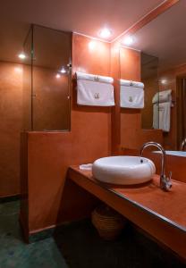 a bathroom with a sink and a mirror and towels at Riad l'Heure d'Eté in Marrakesh