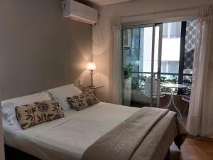 a bedroom with a white bed with a large window at Balcones Verdes 2407 in Salta +31 photos