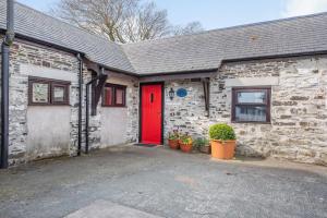a red door on a brick building with potted plants at Stables Cottage in Llanrwst