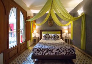 a bedroom with a bed with yellow drapes at Riad l'Heure d'Eté in Marrakesh