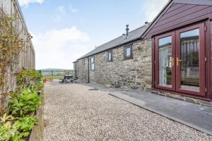 a stone house with a red door and a patio at Dairy Cottage in Llanrwst
