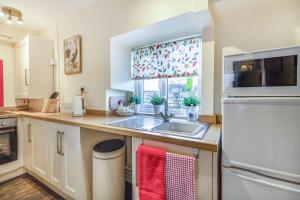 a kitchen with a sink and a refrigerator at Smithy Cottage in Bradwell