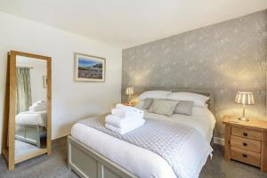 een slaapkamer met een bed met witte lakens en een spiegel bij Smithy Cottage in Bradwell