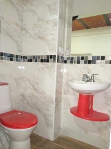 uma casa de banho com um WC vermelho e um lavatório. em Lindo apartamento vacacional en guaduas em Guaduas