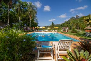 a swimming pool with two chairs and umbrellas at Estância Canaã Atibaia in Atibaia