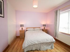 1 dormitorio con 1 cama y 2 mesitas de noche con lámparas en Carnmore Cottage, en Dungloe