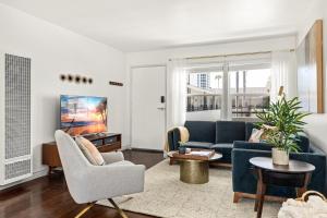 a living room with a blue couch and chairs at Spacious Coastal Apartment in a Colorful Community - NRP22-00590 in Long Beach