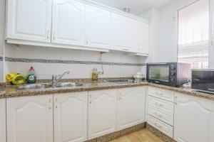 eine Küche mit weißen Schränken und einer Spüle und einer Mikrowelle in der Unterkunft JUDERIA CENTER PREMIUM SUITES FREE Parking in Sevilla