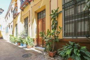 ein gelbes Gebäude mit Topfpflanzen auf einer Straße in der Unterkunft JUDERIA CENTER PREMIUM SUITES FREE Parking in Sevilla
