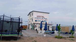 um hotel com cadeiras e guarda-sóis em frente a um edifício em Hostal LAS GARZAS DEL PELADO em Playas