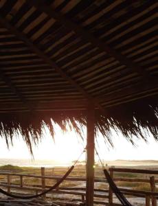 uma rede debaixo de um telhado de palha numa praia em Hostal LAS GARZAS DEL PELADO em Playas