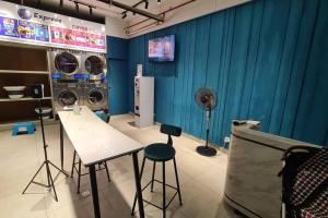 a room with two washing machines and a table and stool at Aeropod [5B]/Near Airport / 2 Queen Bed/ Netflix/Free Parking in Kota Kinabalu